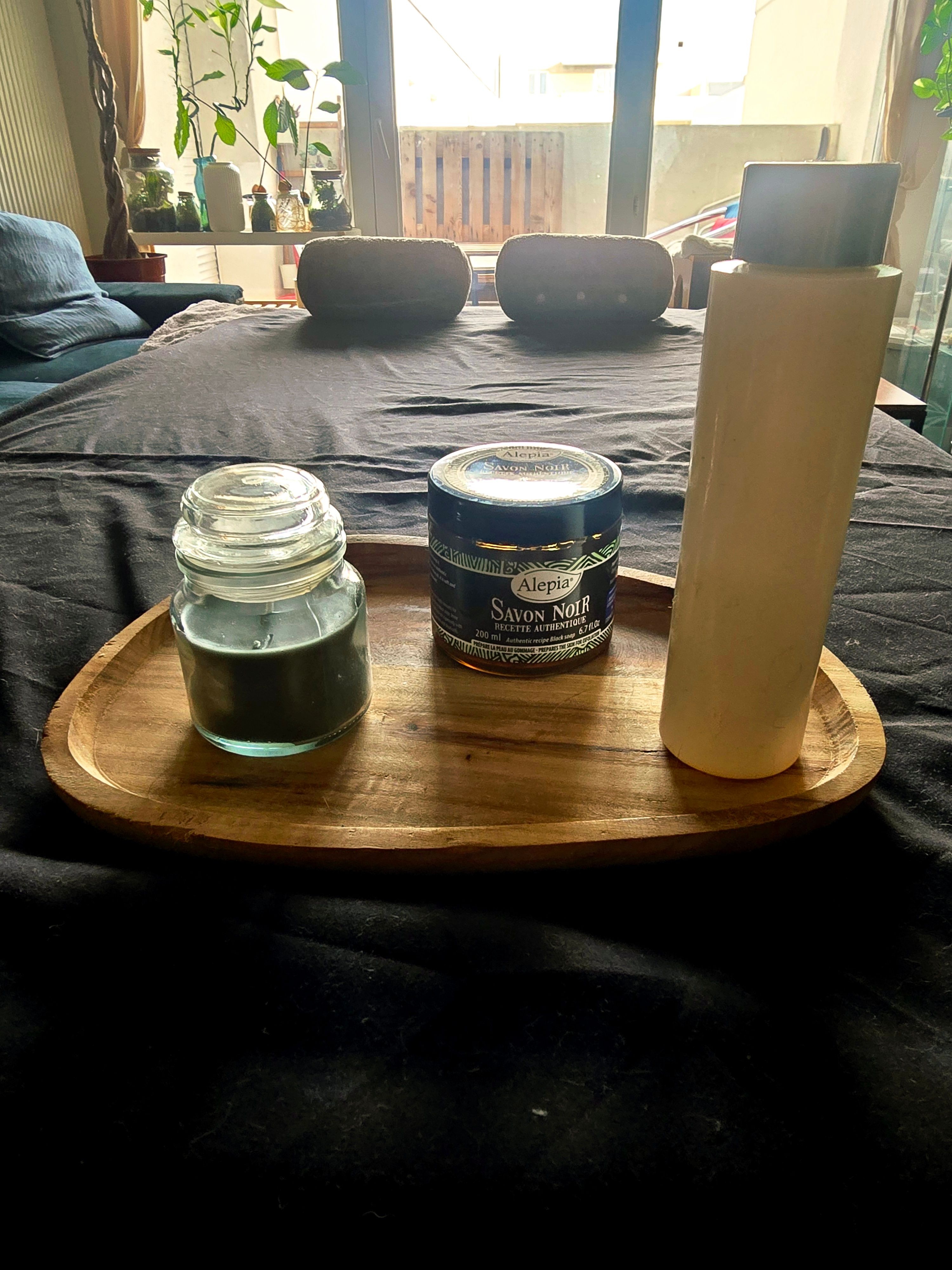 Plateau avec gommage de savon noir, une bouteille d'huile de massage posé sur la table de massage